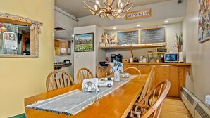 A restaurant with a long wooden table, chairs, a chandelier, a chalkboard menu, and a sign reading "QUIPQUOIA." - Qupqugiaq Inn (Anchorage)