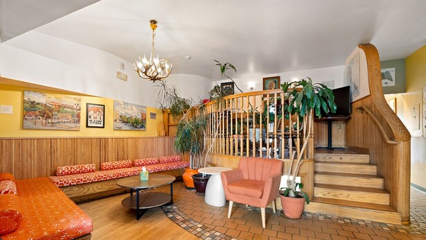 A cozy interior with a wooden staircase, a sofa set, a round table, and potted plants. - Qupqugiaq Inn (Anchorage)