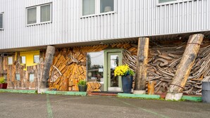 A building with a rustic exterior, featuring wooden logs and a green door. - Qupqugiaq Inn (Anchorage)
