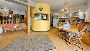 A cozy interior with a wooden dining table, chairs, a rug, and a staircase leading to a second floor. - Qupqugiaq Inn (Anchorage)