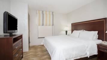Una habitación de hotel con una cama, un televisor en una cómoda, una lámpara y una mesita de noche.