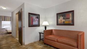 Una habitación de hotel con una cama, un sofá, una lámpara y dos cuadros en la pared.