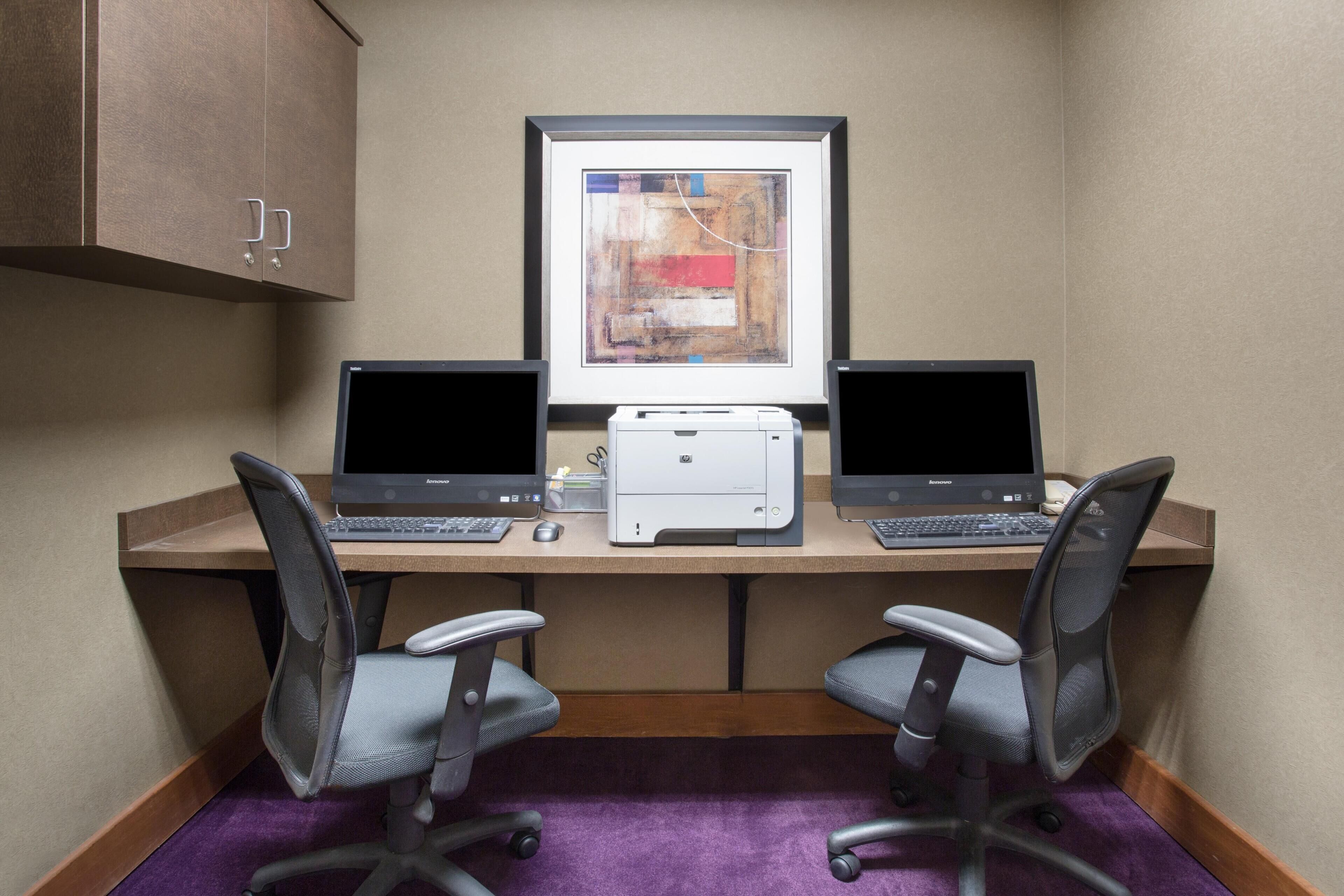 A workspace with two laptops, a printer, and two office chairs.