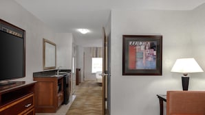 Ett hotellrum med en tv, en inramad tavla, en lampa och en soffa.