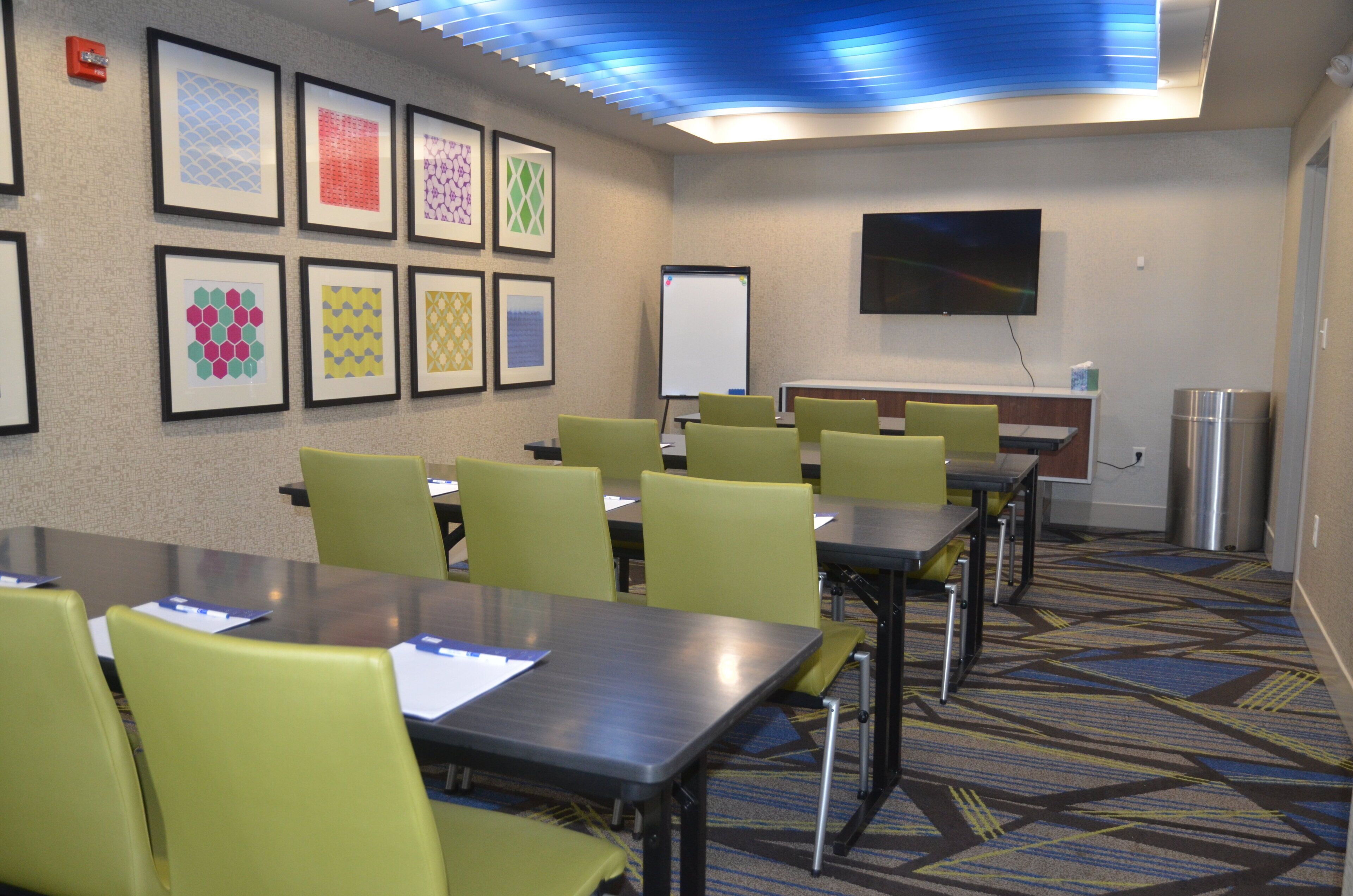 A conference room with tables and chairs, a whiteboard, and framed artwork on the wall.