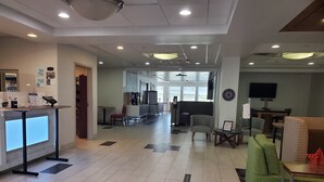 Een hotel lobby met een receptiebalie, een zithoek en een televisie.