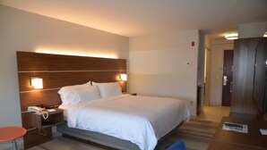 Een hotelkamer met een groot bed, bedlampen, een bureau en een stoel.
