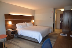 A hotel room with a large bed, bedside lamps, a desk, and a chair.