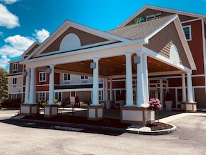 A Holiday Inn Express building with a covered outdoor area, columns, and a landscaped entrance.