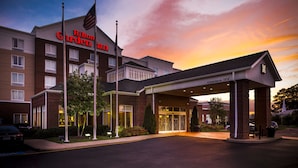 A Hilton Garden Inn with a clear entrance, a flag, and a covered area with a sign indicating clearance. - Hilton Garden Inn Hampton Coliseum Central (Hampton)