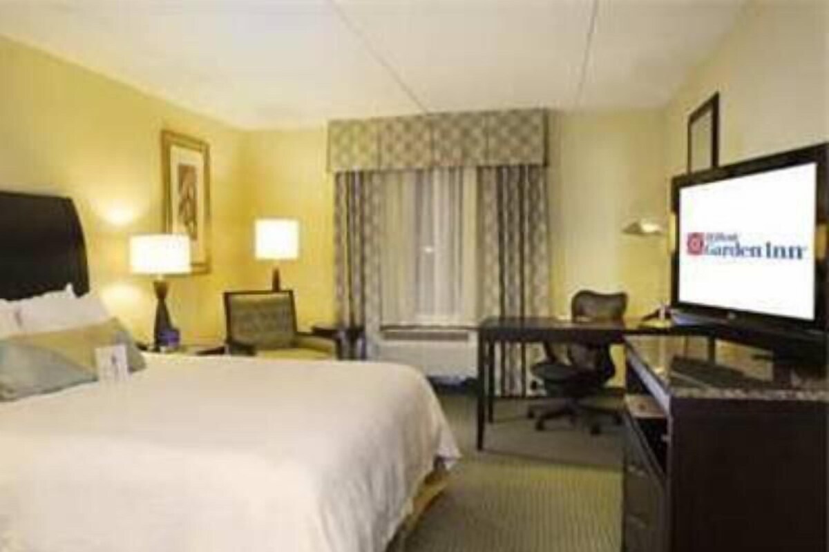 A hotel room with a bed, a desk, a chair, a television, and a window with curtains.