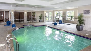 Una piscina interior con agua cristalina, un puesto de socorrista y un letrero que indica que no se permite la entrada de niños sin supervisión de un adulto.