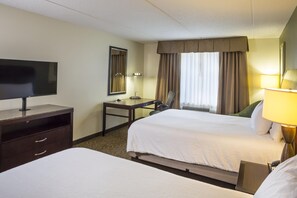 A hotel room with two beds, a desk, a chair, a television, and a window with curtains. - Hilton Garden Inn Hampton Coliseum Central (Hampton)