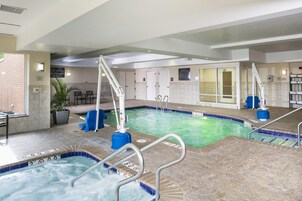 Zona de piscina de hotel con varias piscinas, puestos de socorristas y un letrero que indica 'no saltos'.