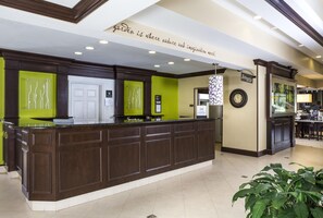 A reception desk with a sign above stating 'garden is where nature and imagination meet.' - Hilton Garden Inn Hampton Coliseum Central (Hampton)