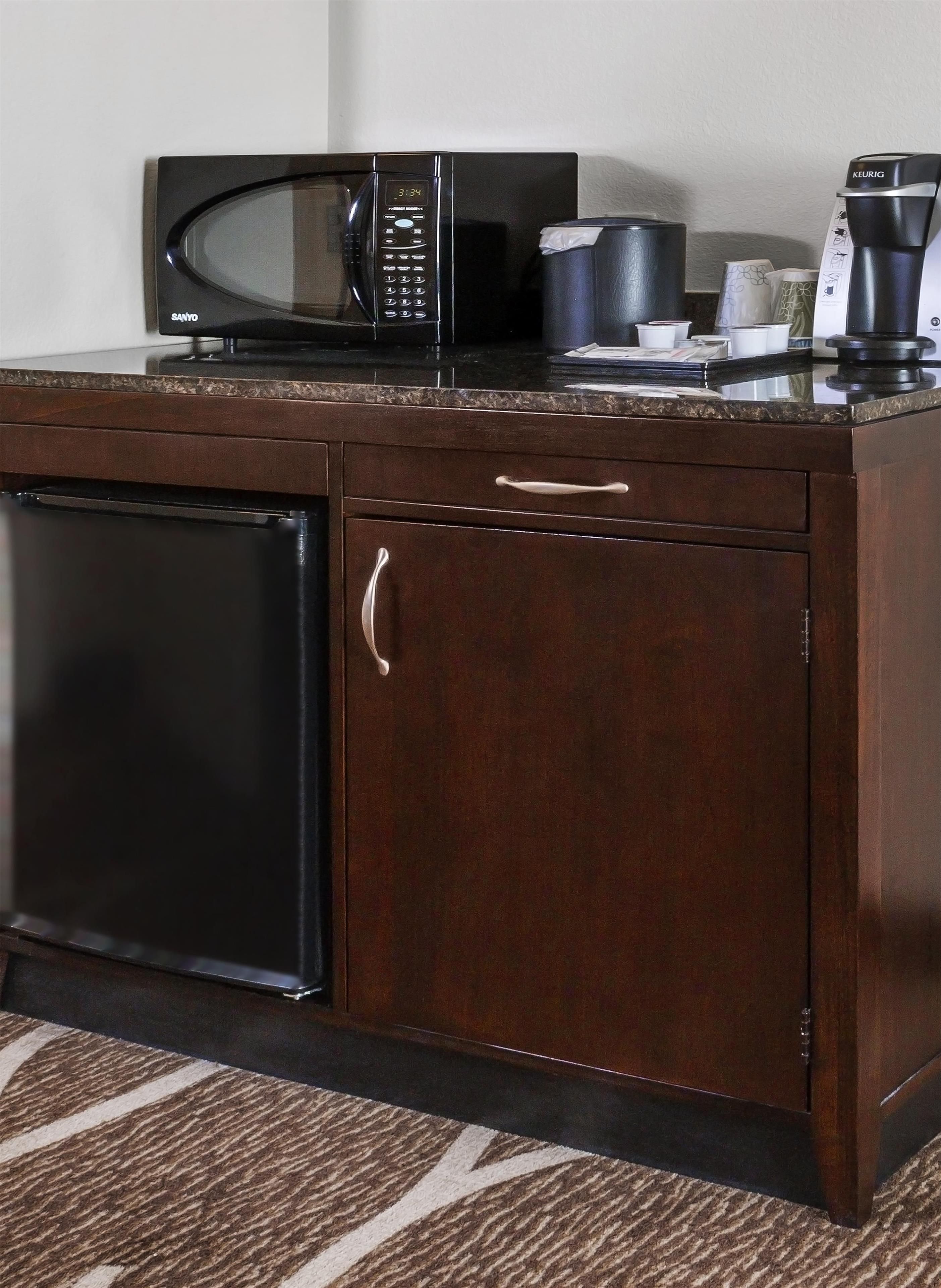 Una cocina compacta con microondas, cafetera y refrigerador pequeño.