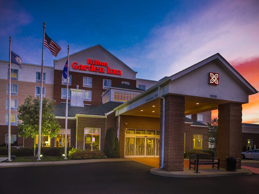 Un Hilton Garden Inn con entrada despejada, exhibición de banderas y un letrero que indica el año 1998.