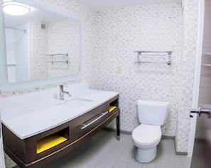 A modern bathroom with a white sink, a mirror, a toilet, and patterned wallpaper. - Holiday Inn & Suites Stockbridge/Atlanta I-75 by IHG (Stockbridge)