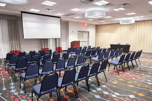 A conference room with rows of chairs, a projection screen, and a podium.