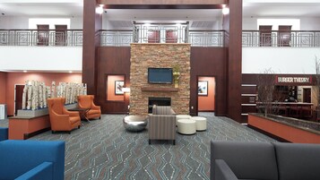 A hotel lobby with a stone fireplace, seating area, and a restaurant named 'Burger Theory'.