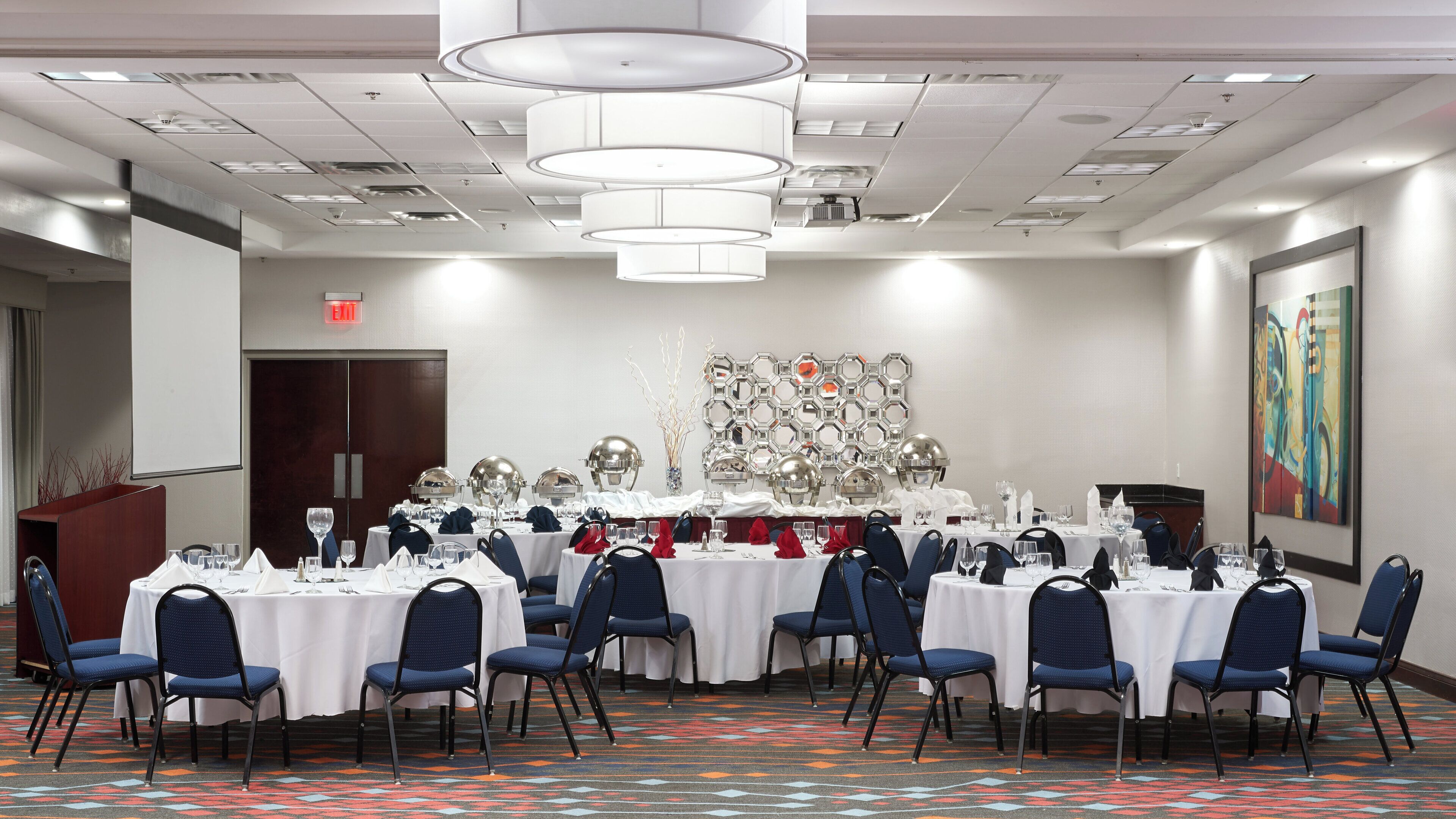 A conference room with round tables, chairs, and a decorative wall.