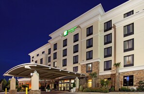A Holiday Inn & Suites hotel with a covered entrance, stone facade, and multiple windows. - Holiday Inn & Suites Stockbridge/Atlanta I-75 by IHG (Stockbridge)