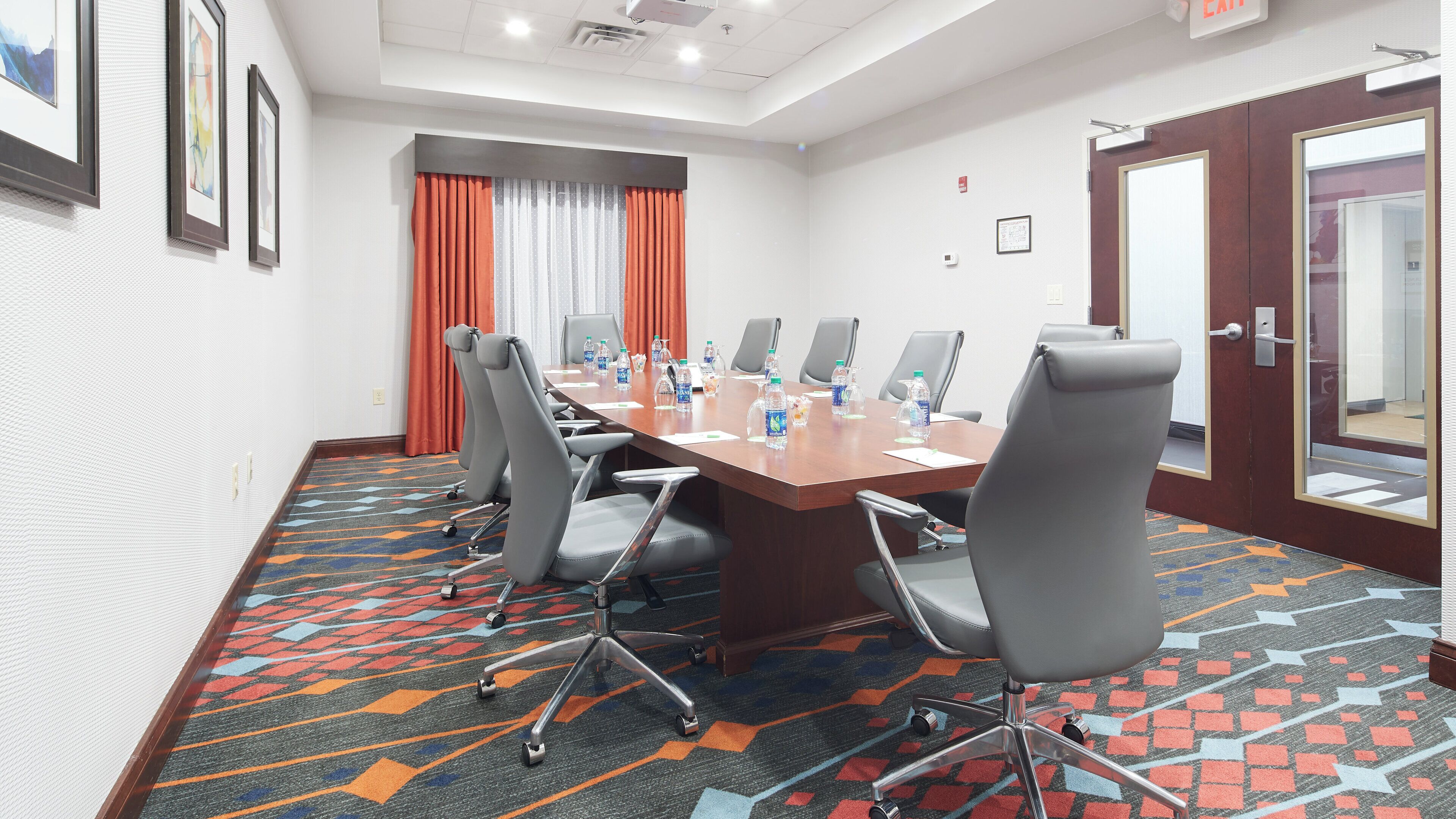 Un salón de conferencias con una mesa larga, varias sillas y piso alfombrado.