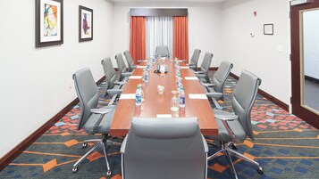 A conference room with a long table, chairs, water bottles, and a telephone.