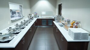 A modern kitchen with stainless steel appliances, a long counter with multiple serving stations, and a central island. - Holiday Inn & Suites Stockbridge/Atlanta I-75 by IHG (Stockbridge)