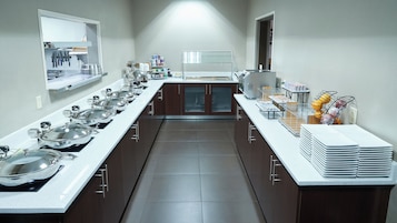 Uma cozinha moderna com eletrodomésticos de aço inoxidável, uma bancada extensa com vários pontos de apoio e uma ilha central.