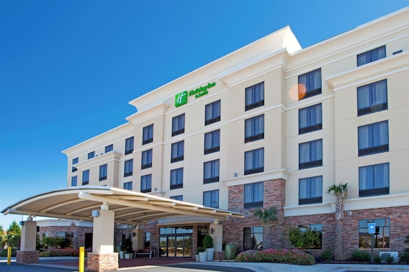 A hotel with a modern facade, multiple floors, and a covered entrance area.