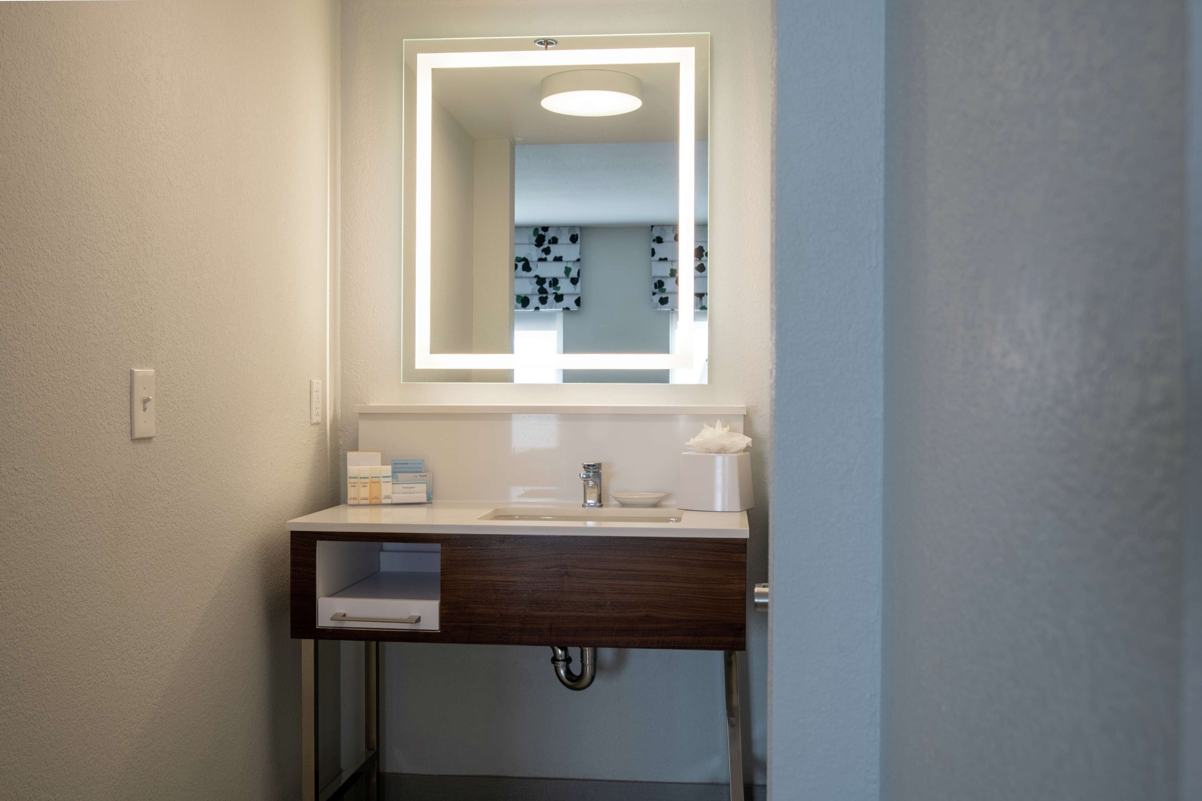A bathroom with a white sink, a mirror, and a towel holder.