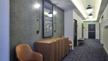 A reception area with a wooden reception desk, two leather chairs, a bench, and framed artwork on the wall.