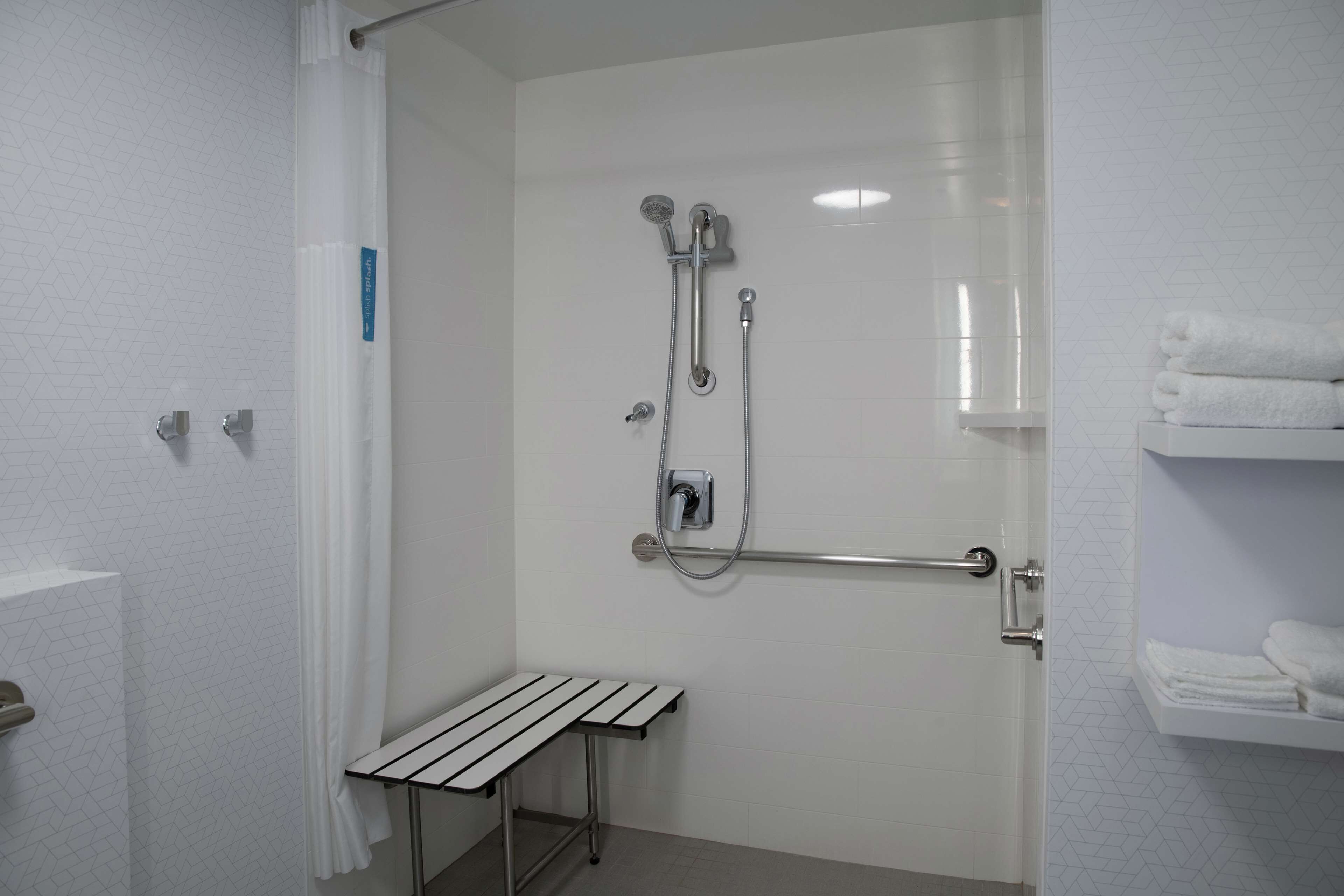 A bathroom with a shower, a towel rack, and a small table.