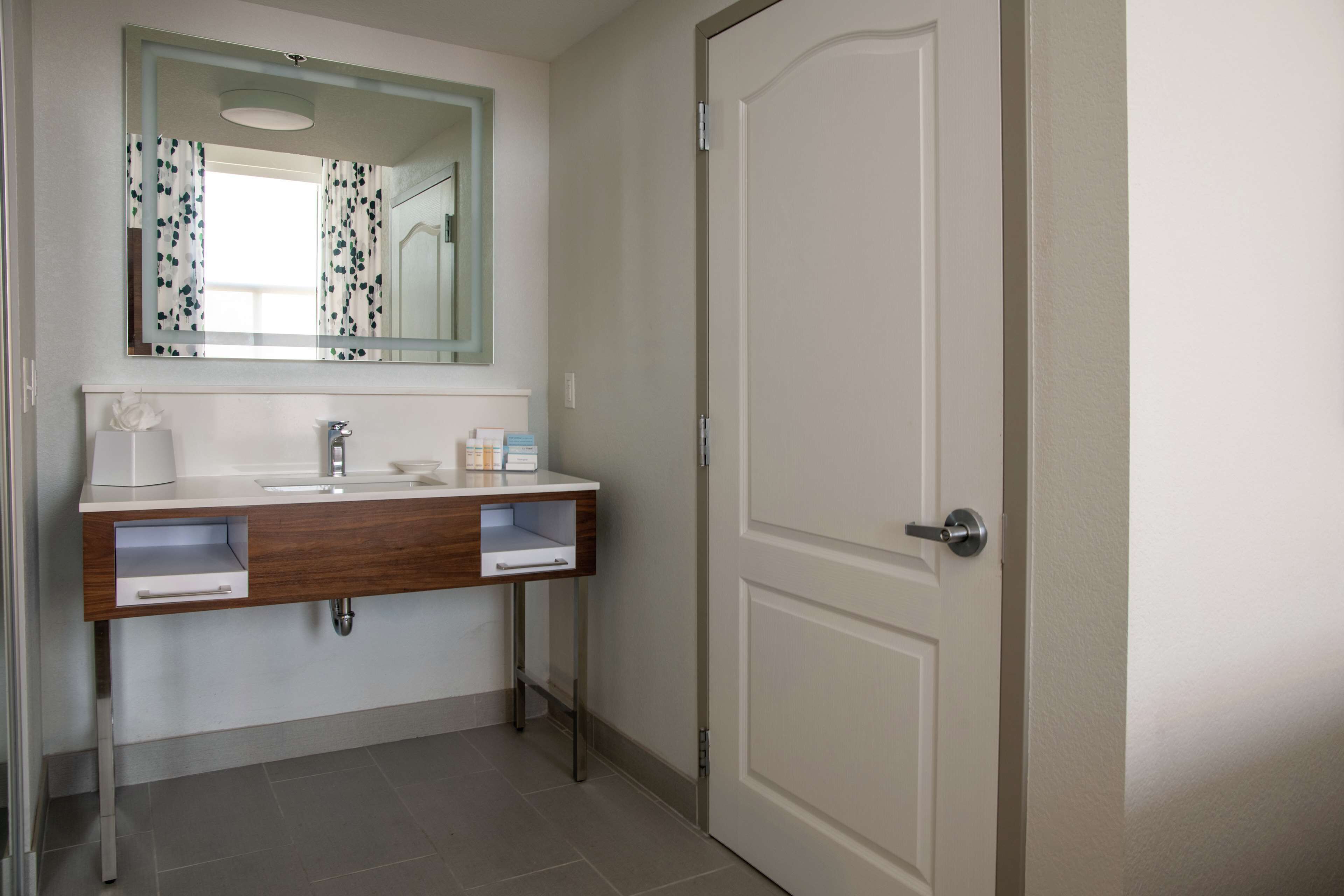 A bathroom with a white sink, a mirror, and a door.