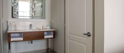 A bathroom with a white sink, a mirror, and a door.