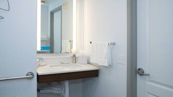 A modern bathroom with a white sink, a mirror, and a towel rack.