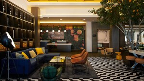 A modern lobby with a reception desk, sofas, chairs, and a patterned floor. - Hampton Inn & Suites Los Angeles/Sherman Oaks (Van Nuys)