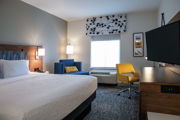 A hotel room with a large bed, a desk, a chair, a television, and a window with a view. - Hampton Inn & Suites Los Angeles/Sherman Oaks (Van Nuys)
