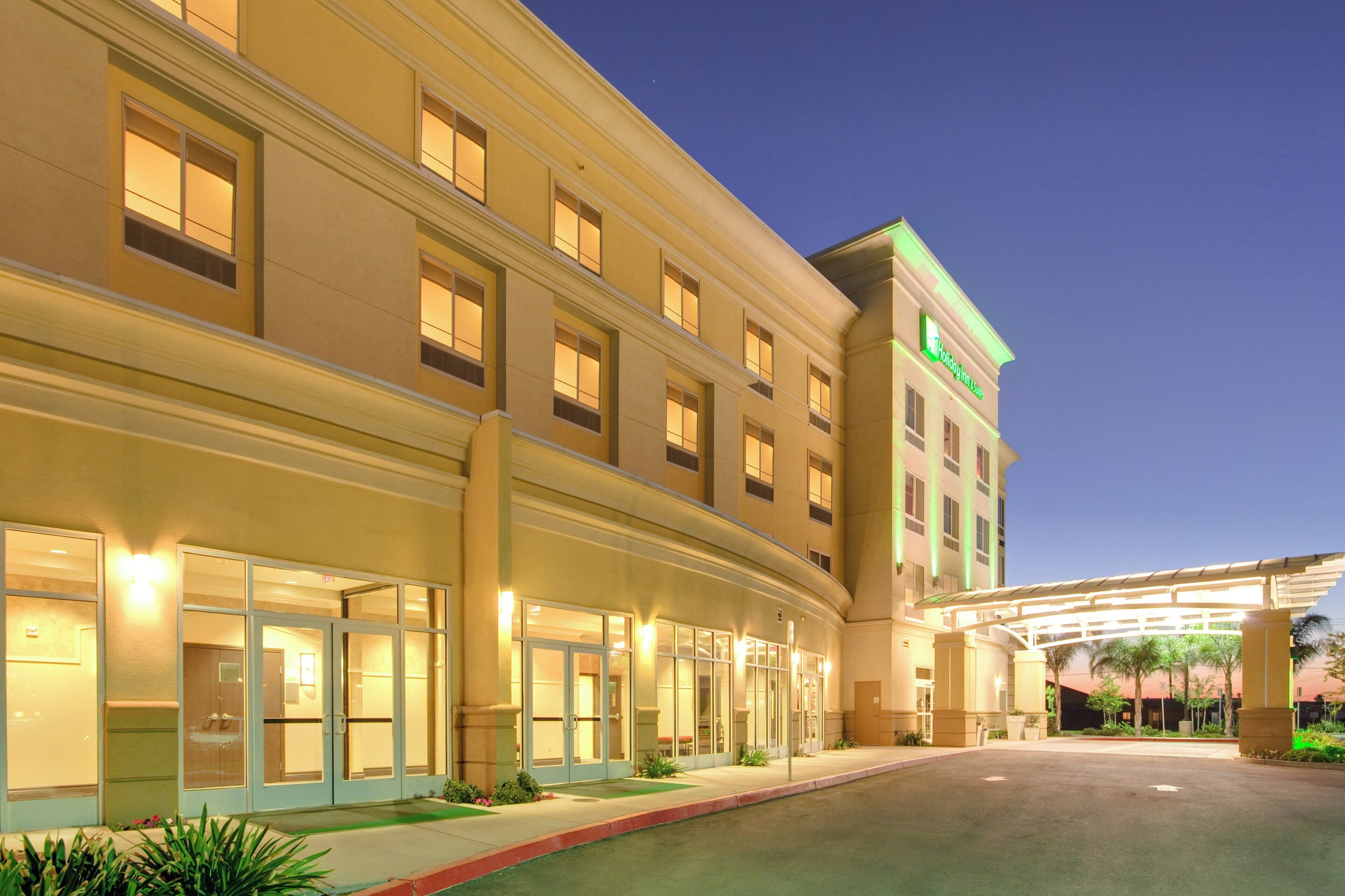 A multi-story hotel with a covered entrance and a landscaped driveway.
