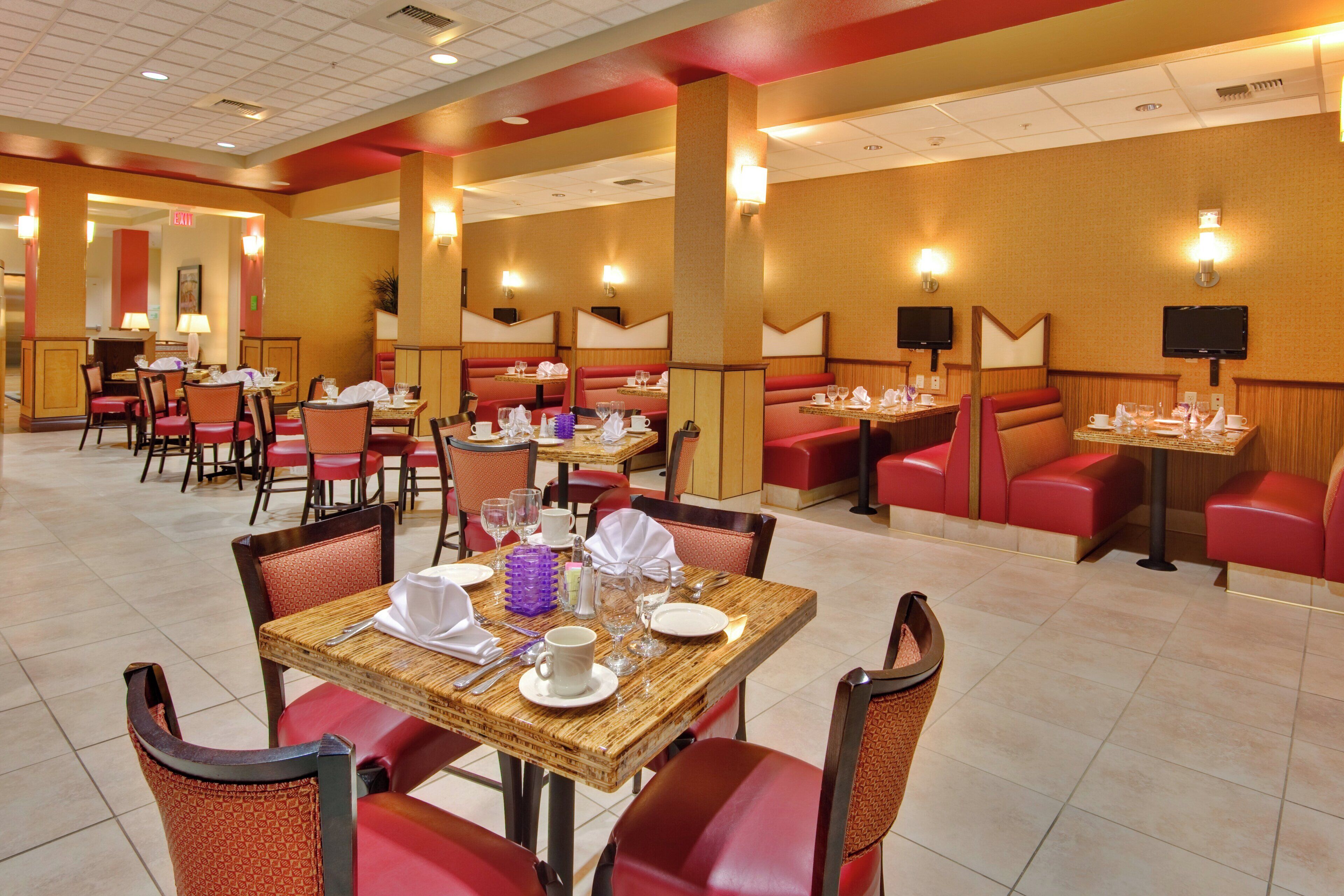 A restaurant with booths and tables, equipped with chairs, tables, and various dining utensils.