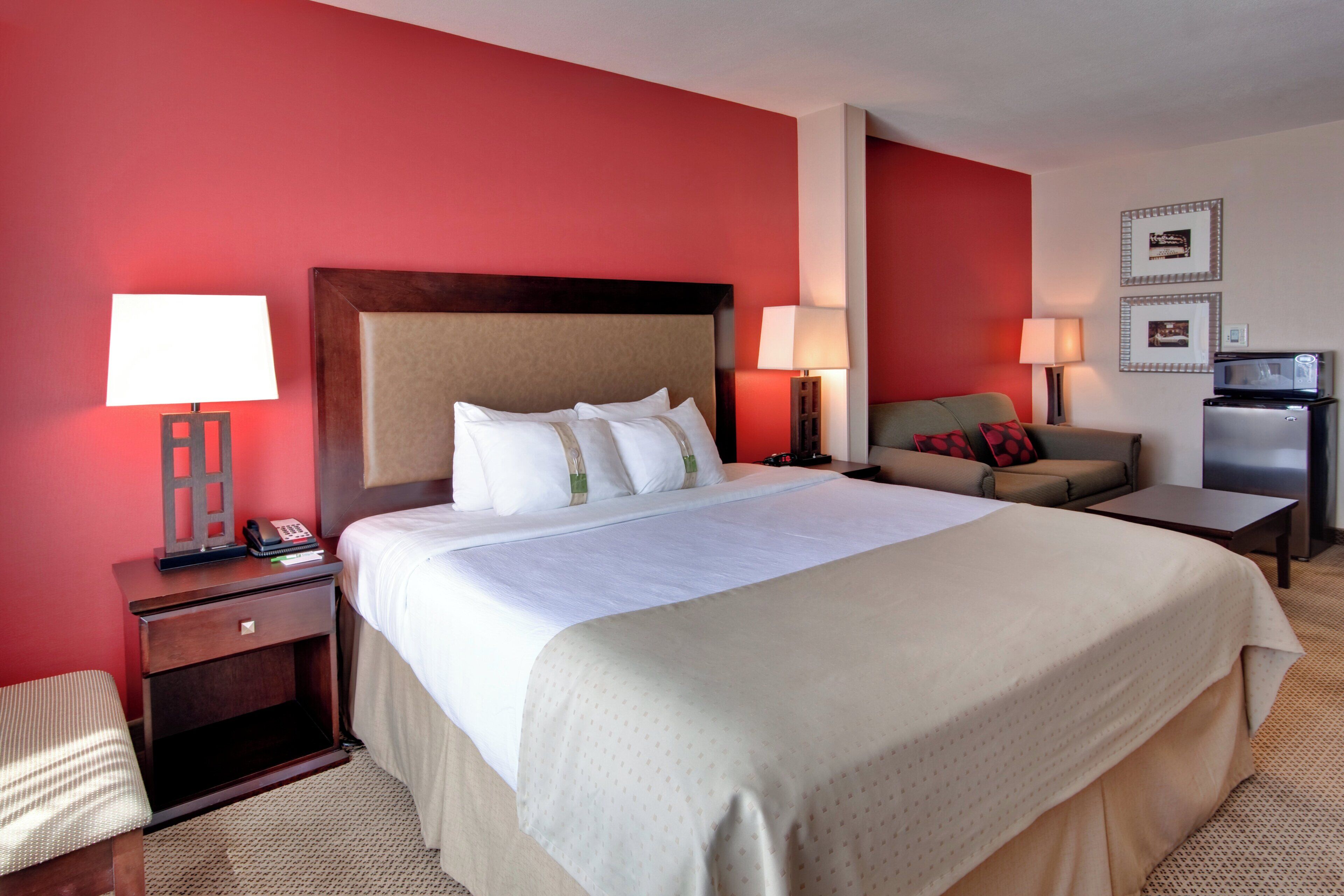 A hotel room with a large bed, bedside lamps, a desk, a chair, and a television.