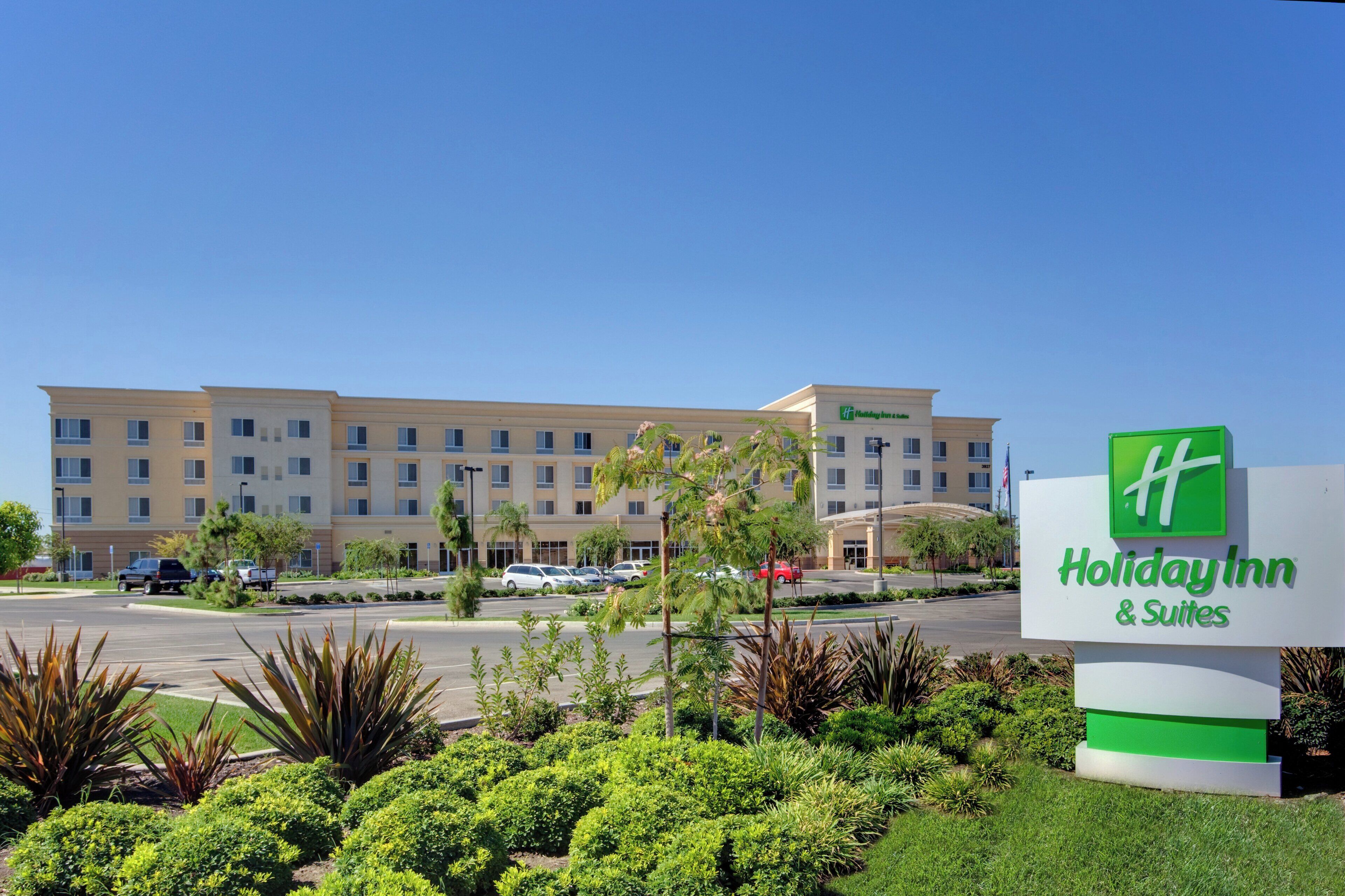 Un hôtel Holiday Inn & Suites doté d’un grand bâtiment, d’un parking et d’un aménagement paysager bien entretenu.
