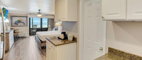 A kitchen with white cabinets, a granite countertop, and a view to the outside.