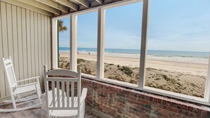 A room with a view of the beach, a rocking chair, and a brick wall. - The Oceanfront Litchfield Inn (Pawleys Island)