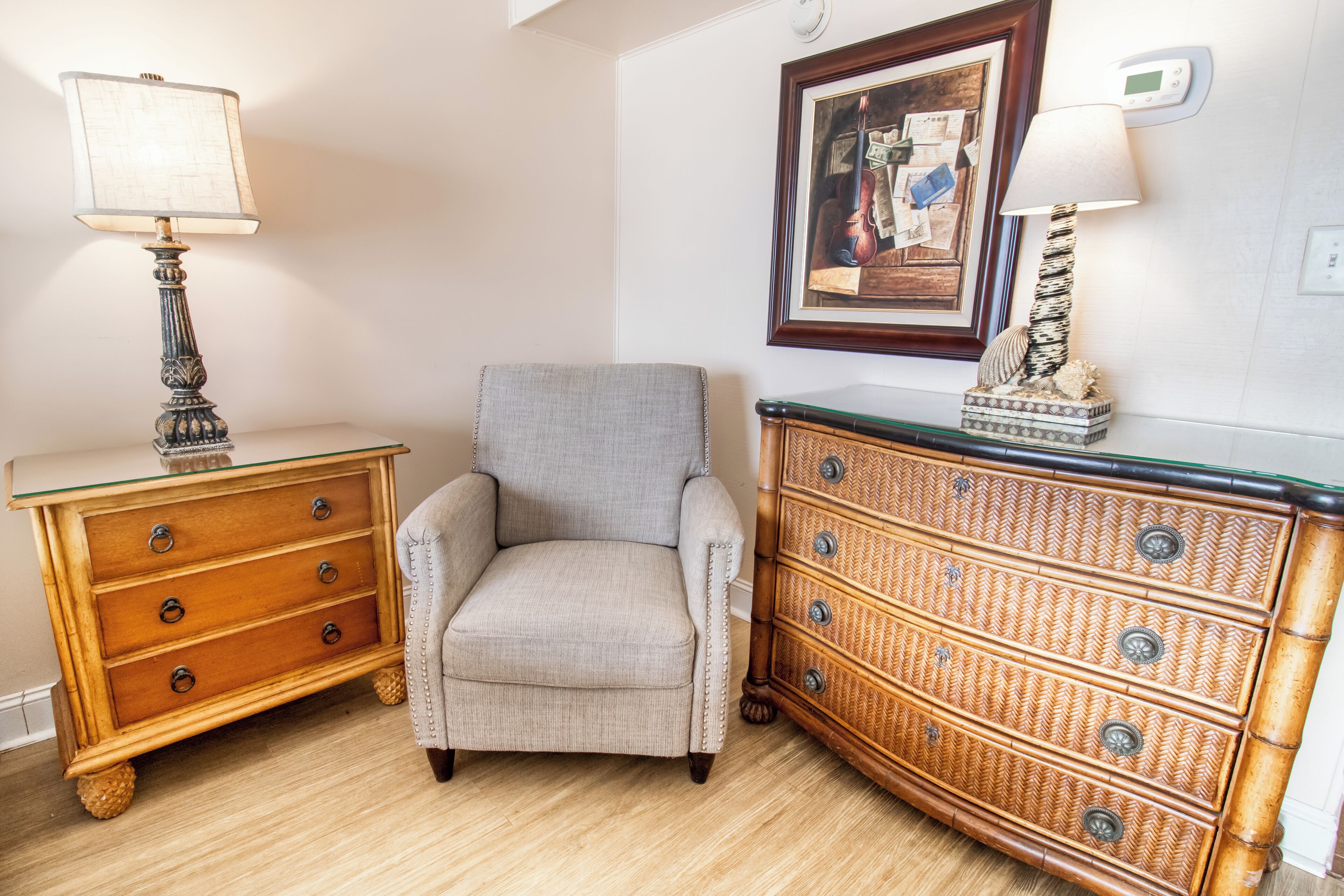 A room with a wooden dresser, a chair, and a lamp.