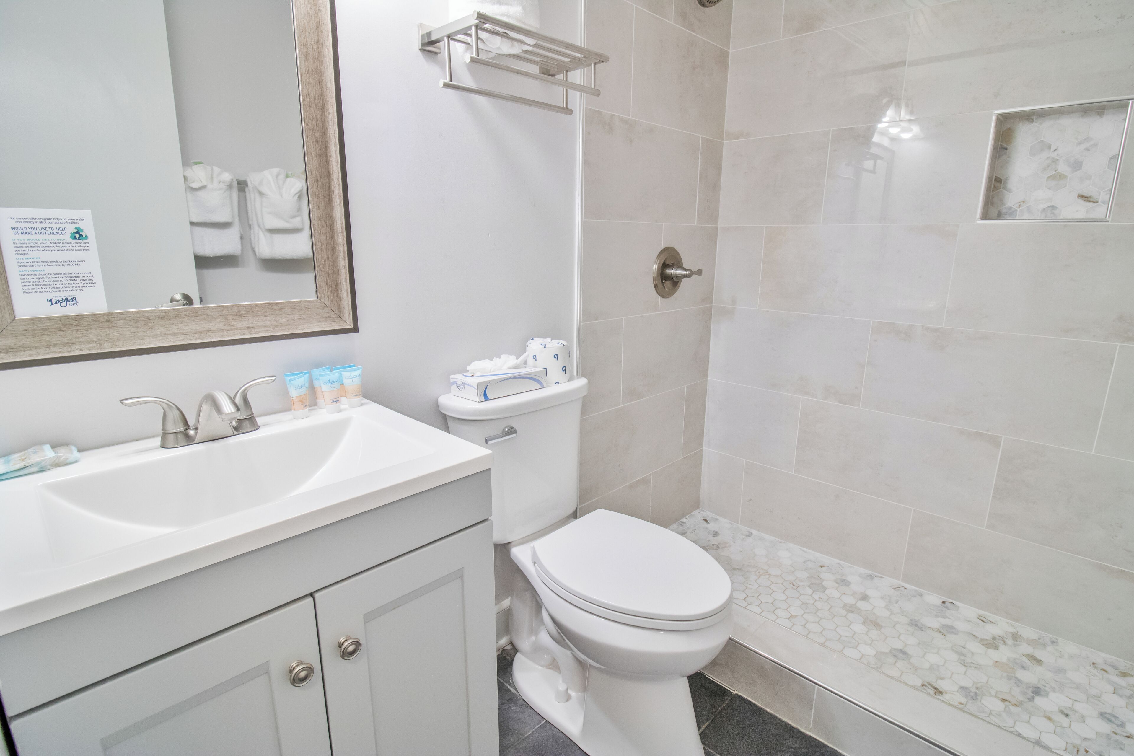 Un baño moderno con lavamanos, inodoro y ducha blancos.
