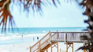 A wooden beach deck with a staircase leading to the sand, overlooking the ocean. - The Oceanfront Litchfield Inn (Pawleys Island)