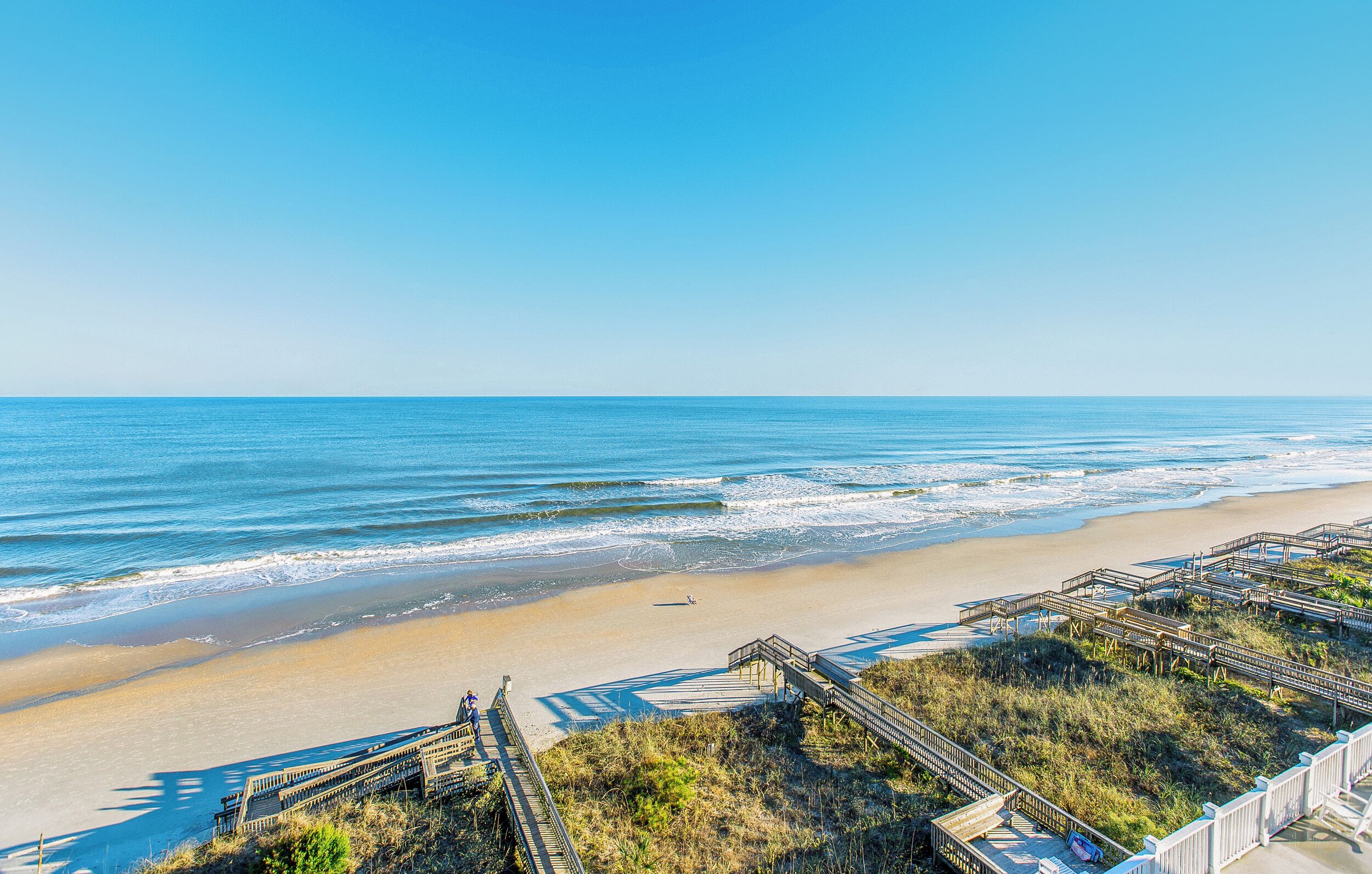 Une plage avec des promenades en bois et une vue dégagée sur l’océan.