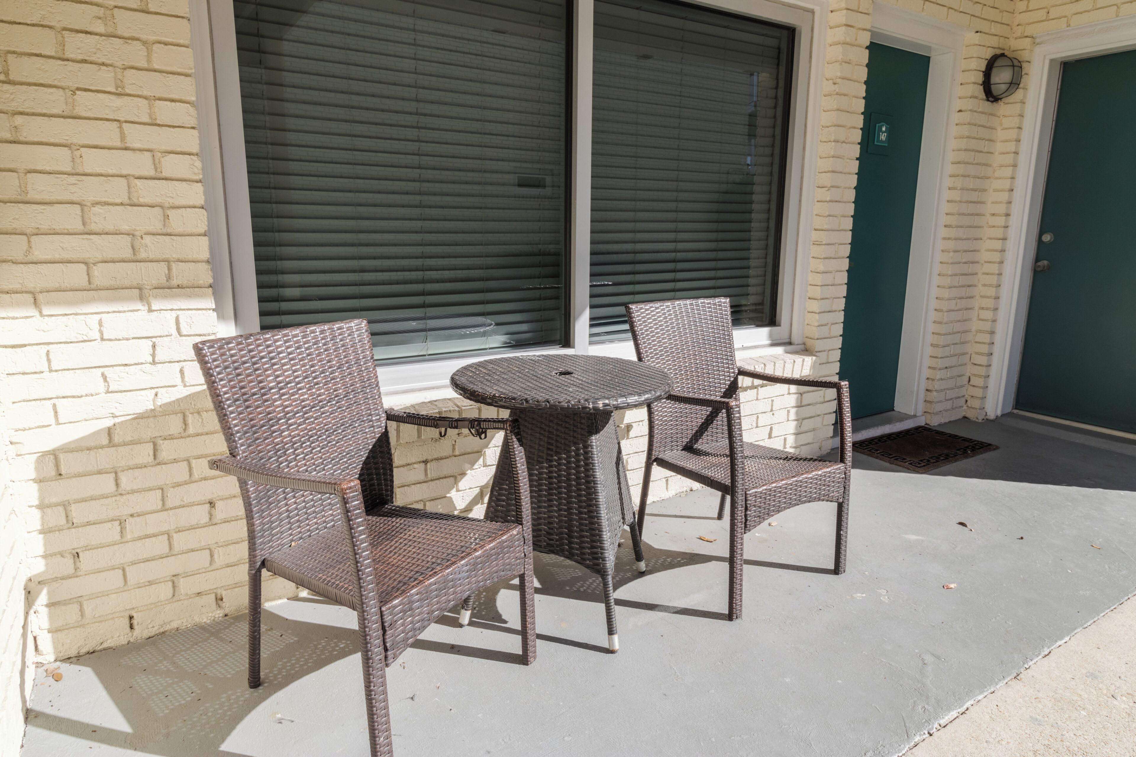A patio with wicker furniture, a brick wall, and a green door.